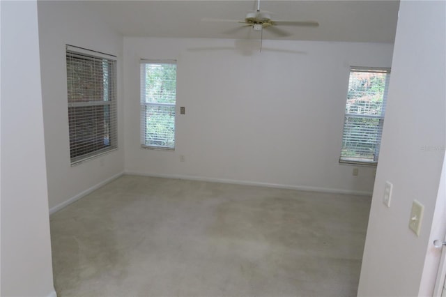 carpeted spare room featuring plenty of natural light and ceiling fan