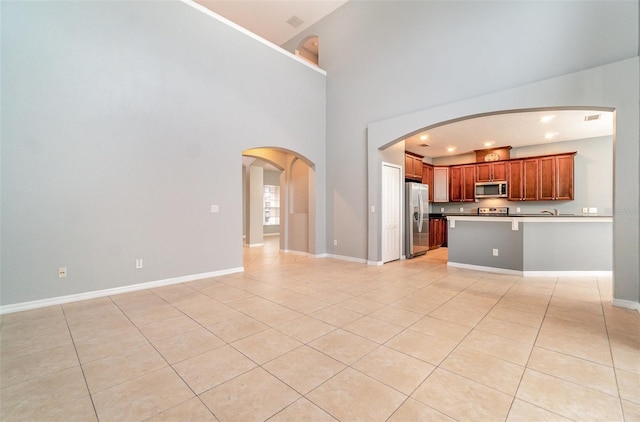 unfurnished living room with a high ceiling and light tile patterned flooring