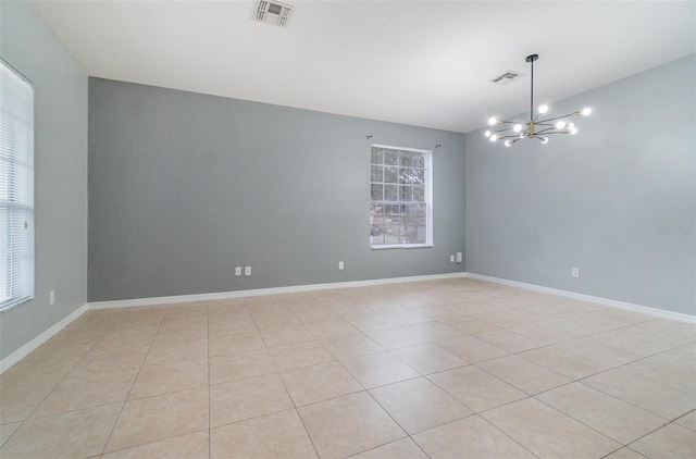 tiled spare room featuring a notable chandelier