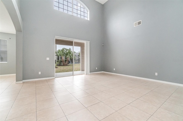 spare room featuring light tile patterned floors and a high ceiling