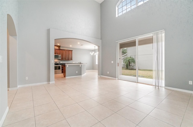 unfurnished living room featuring an inviting chandelier, a high ceiling, and light tile patterned flooring