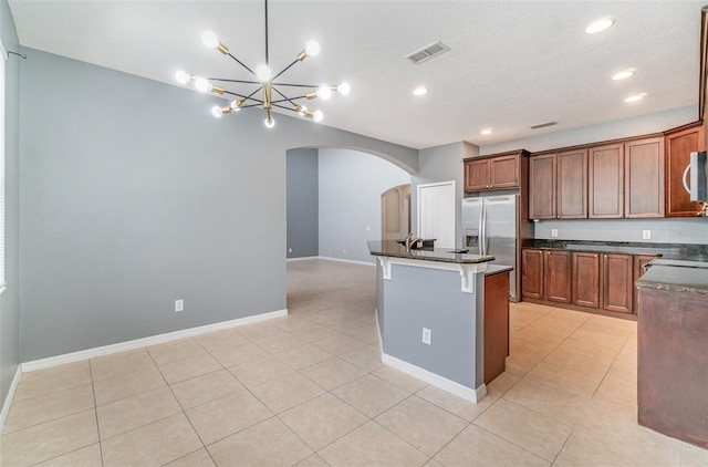 kitchen with stainless steel appliances, light tile patterned flooring, a kitchen island, and a breakfast bar