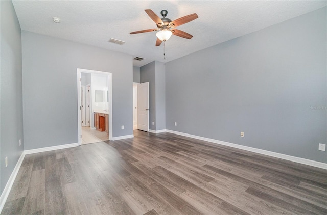 unfurnished bedroom with ceiling fan, dark wood-type flooring, a textured ceiling, and ensuite bath