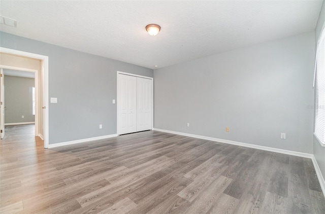 unfurnished bedroom with wood-type flooring, a textured ceiling, and a closet