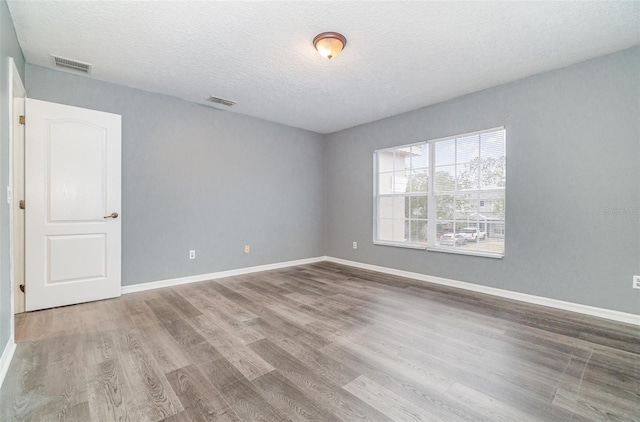 unfurnished room featuring hardwood / wood-style floors and a textured ceiling