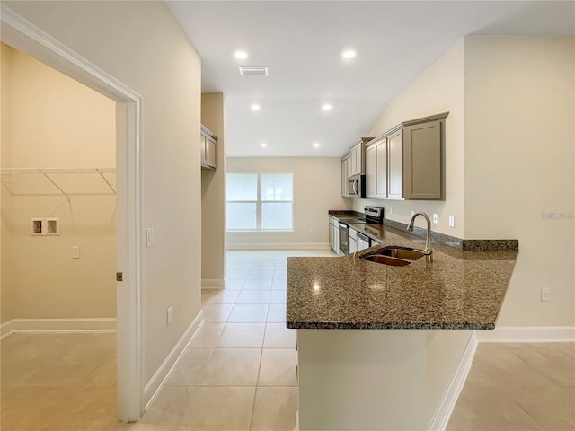 kitchen with sink, dark stone counters, light tile patterned floors, kitchen peninsula, and stainless steel appliances