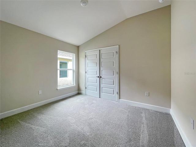 unfurnished bedroom featuring lofted ceiling, carpet flooring, and a closet