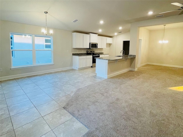 kitchen featuring appliances with stainless steel finishes, decorative light fixtures, vaulted ceiling, and white cabinets