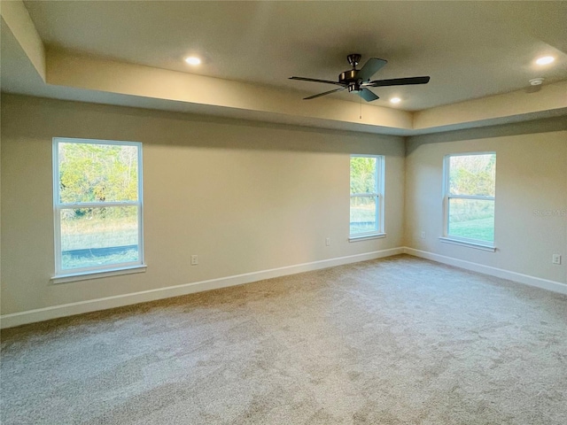 unfurnished room with ceiling fan, carpet flooring, and a tray ceiling