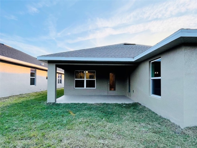 back of house with a patio and a lawn