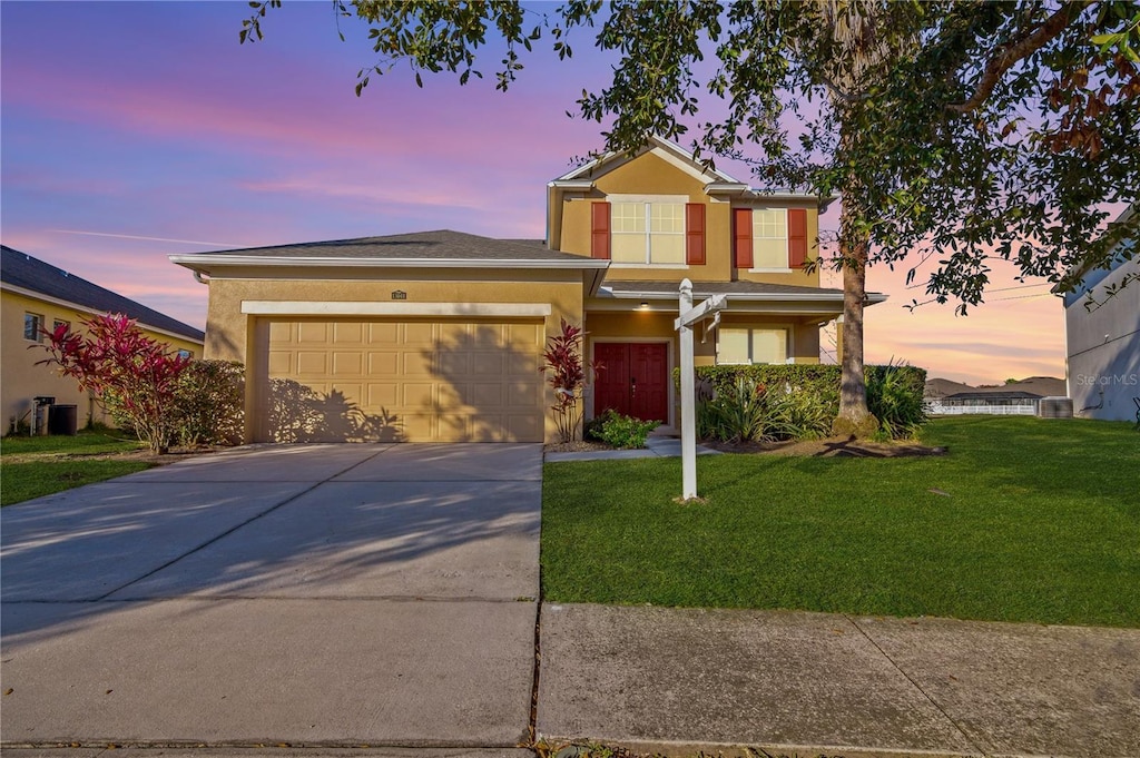 view of front of home with a garage and a lawn