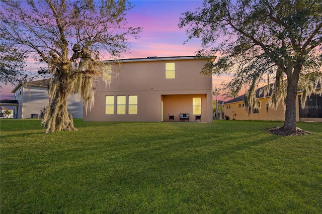 back house at dusk featuring a yard