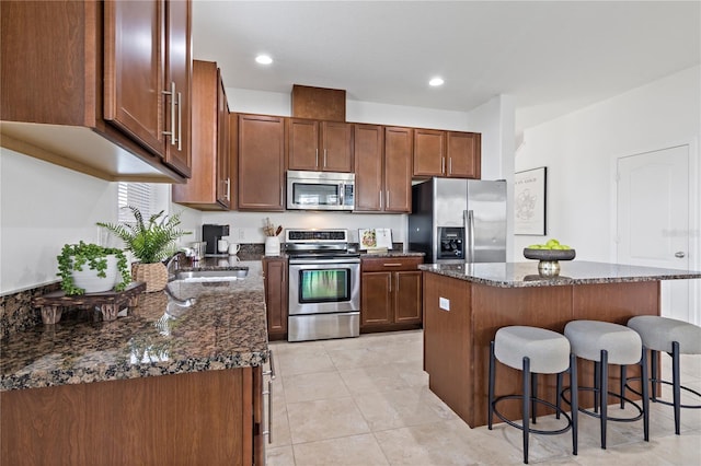 kitchen featuring appliances with stainless steel finishes, sink, a kitchen island, and dark stone counters