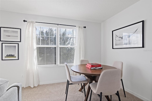 dining area featuring light carpet and a textured ceiling