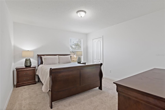 bedroom with light colored carpet, a closet, and a textured ceiling