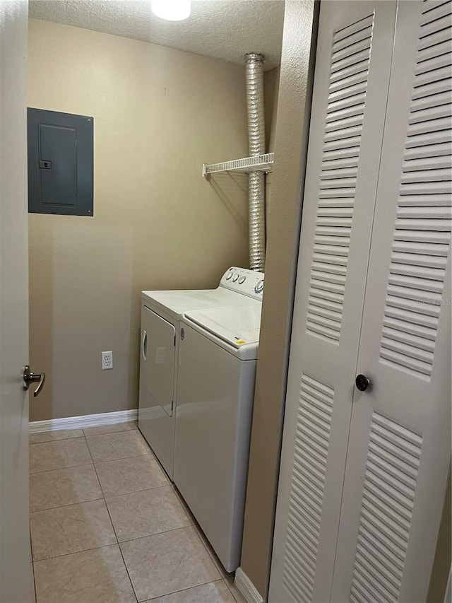 clothes washing area with light tile patterned flooring, electric panel, washing machine and dryer, and a textured ceiling