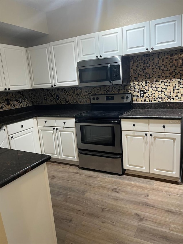 kitchen with white cabinetry, dark stone countertops, decorative backsplash, light hardwood / wood-style floors, and stainless steel appliances