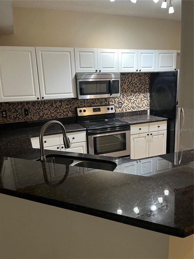 kitchen featuring tasteful backsplash, white cabinetry, sink, dark stone countertops, and stainless steel appliances