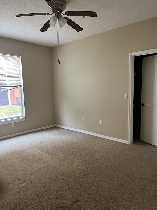 carpeted spare room featuring ceiling fan and a textured ceiling