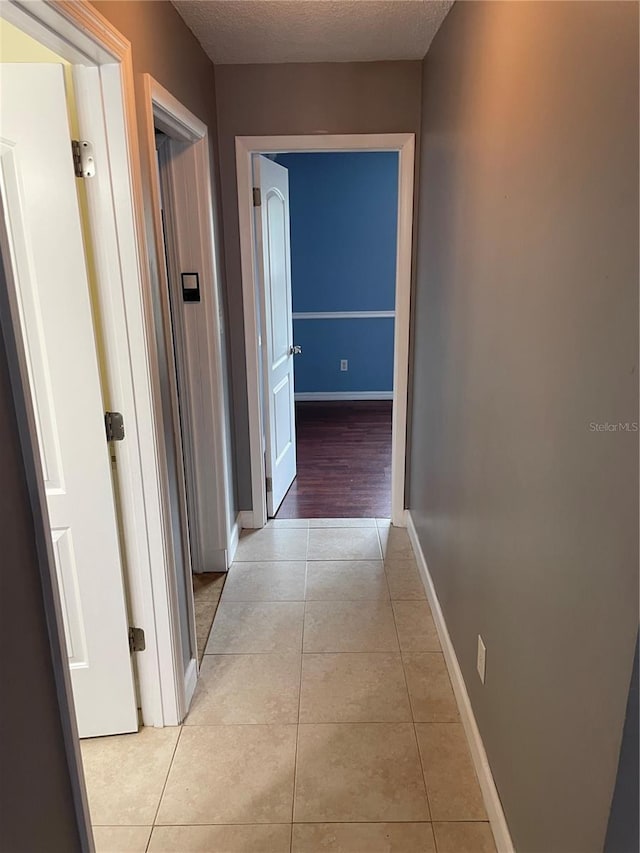 corridor with light tile patterned floors and a textured ceiling