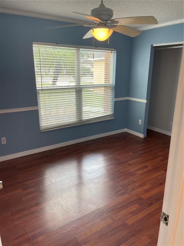 spare room with ceiling fan, ornamental molding, a textured ceiling, and dark hardwood / wood-style flooring