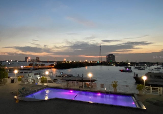 pool at dusk featuring a water view