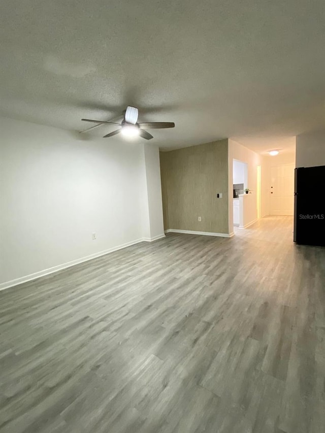 unfurnished living room featuring hardwood / wood-style flooring, ceiling fan, and a textured ceiling