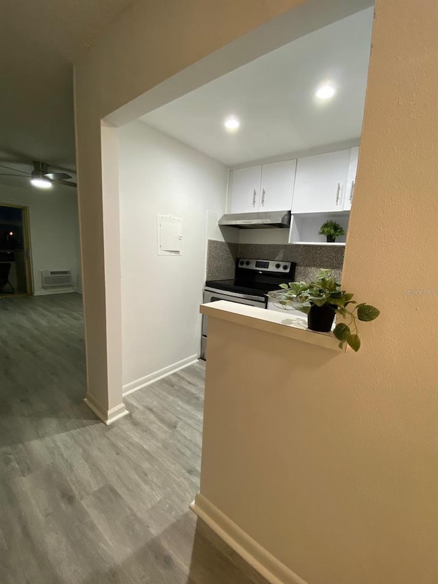 kitchen with white cabinetry, light hardwood / wood-style flooring, electric range, kitchen peninsula, and backsplash