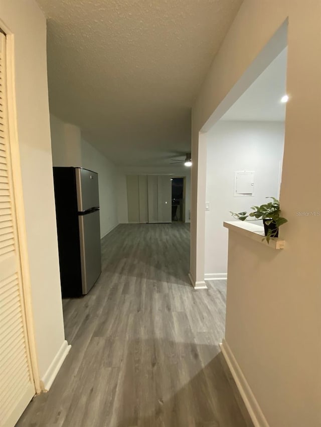 hall with wood-type flooring and a textured ceiling