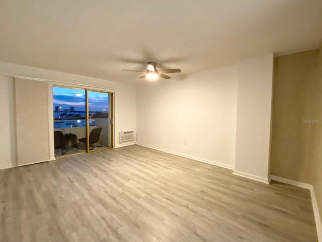 spare room with ceiling fan, a wall mounted air conditioner, and hardwood / wood-style floors