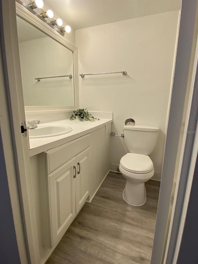 bathroom with wood-type flooring, toilet, and vanity