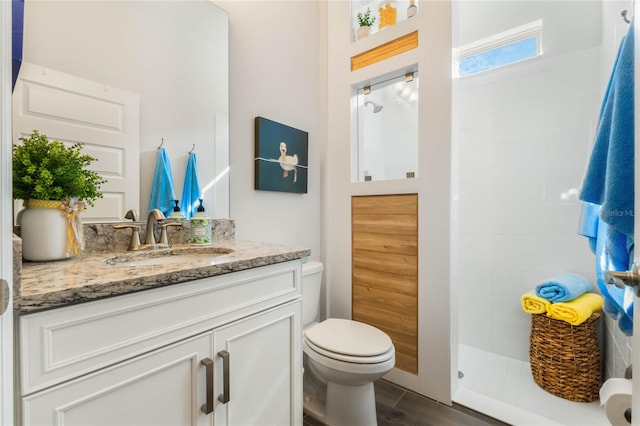 bathroom featuring tiled shower, vanity, and toilet