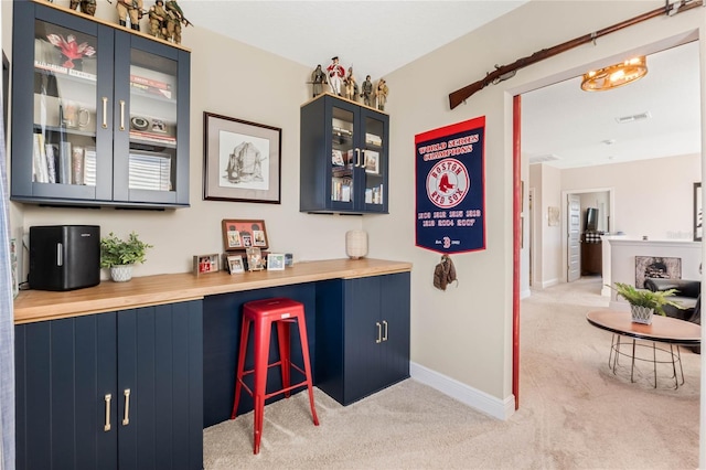 bar featuring light carpet, wood counters, and blue cabinets