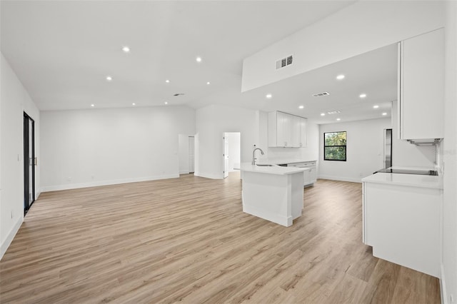 kitchen with sink, kitchen peninsula, white cabinets, and light wood-type flooring