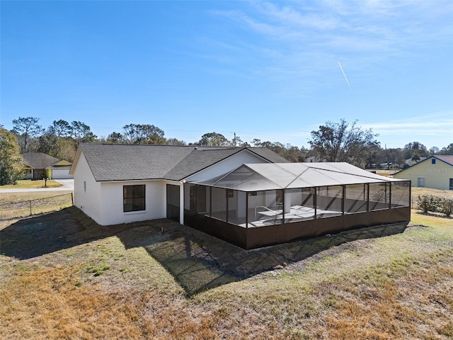 back of house featuring glass enclosure and a lawn