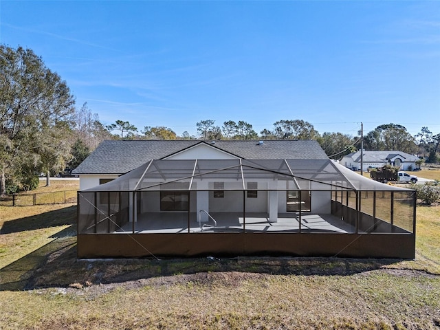 back of house featuring a patio, glass enclosure, and a lawn