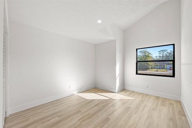 spare room with light hardwood / wood-style flooring and vaulted ceiling