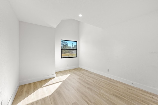 spare room featuring vaulted ceiling and light wood-type flooring