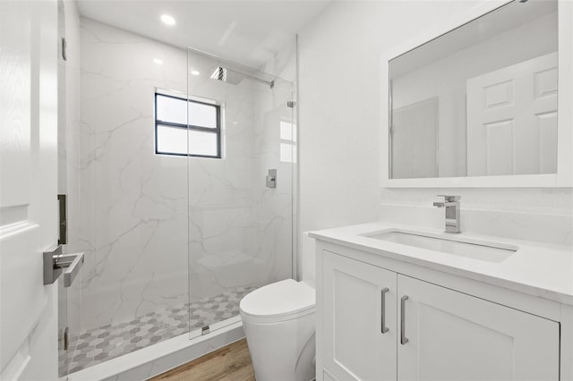 bathroom with hardwood / wood-style flooring, vanity, toilet, and a shower with door