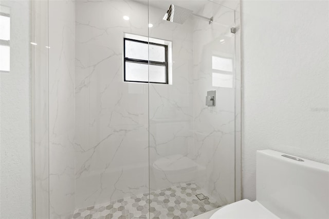 bathroom with a tile shower and toilet