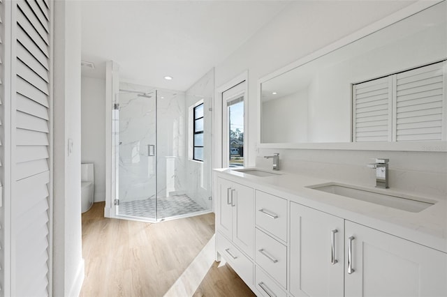 bathroom featuring a shower with door, vanity, hardwood / wood-style floors, and toilet