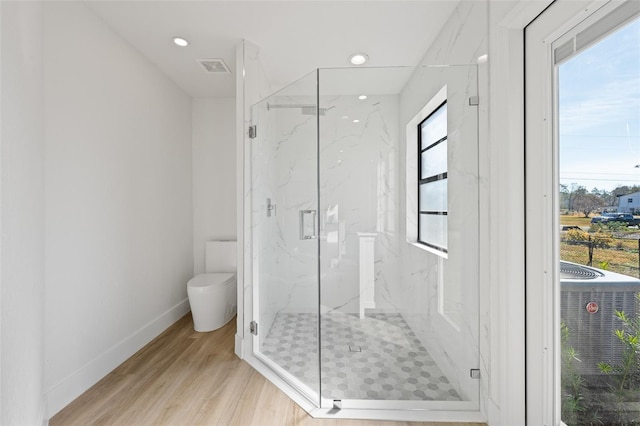 bathroom featuring wood-type flooring, toilet, and a shower with shower door