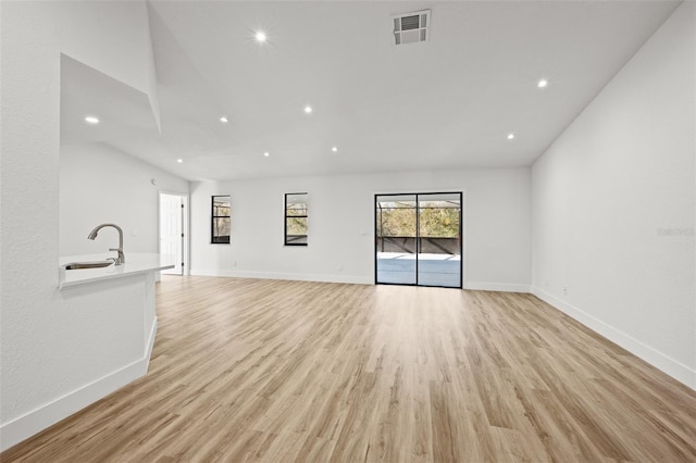 unfurnished living room with sink and light hardwood / wood-style flooring