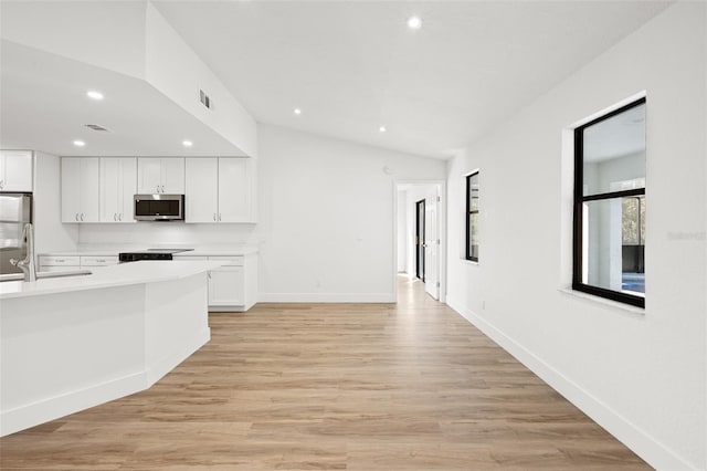 kitchen with white cabinetry, sink, light hardwood / wood-style flooring, and stove