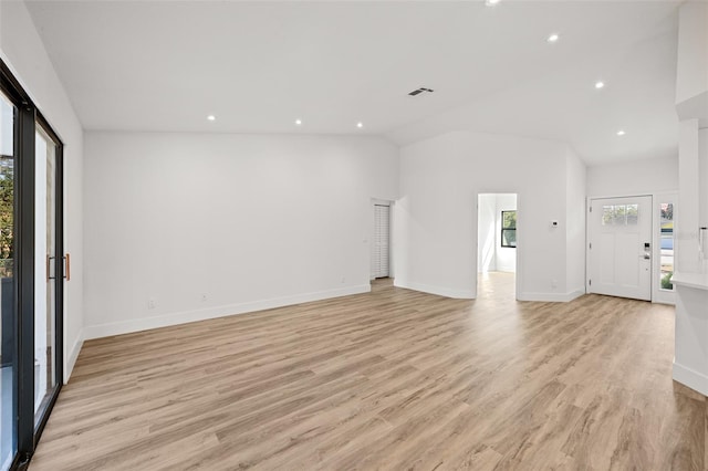 unfurnished living room with light hardwood / wood-style flooring, plenty of natural light, and lofted ceiling