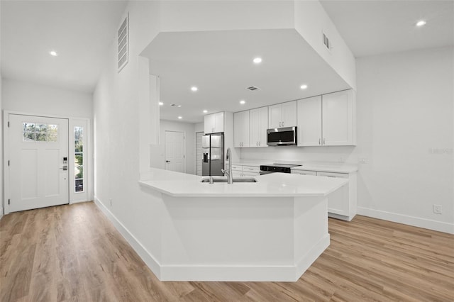 kitchen featuring white cabinetry, stainless steel appliances, kitchen peninsula, and sink