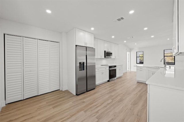 kitchen featuring sink, light wood-type flooring, kitchen peninsula, stainless steel appliances, and white cabinets