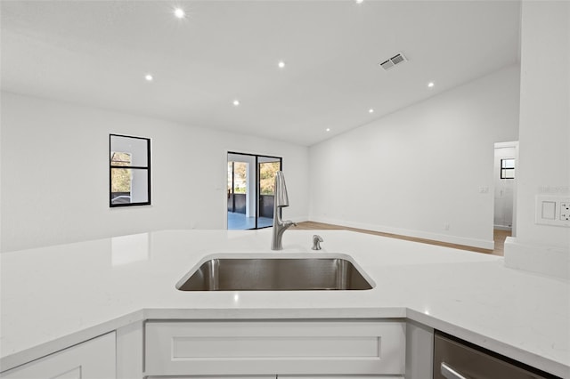 kitchen with sink, stainless steel dishwasher, white cabinets, and light stone counters