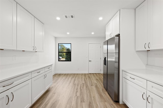 kitchen with white cabinetry, stainless steel fridge, and light hardwood / wood-style flooring