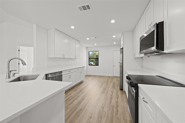 kitchen featuring stainless steel appliances, sink, white cabinets, and light hardwood / wood-style flooring